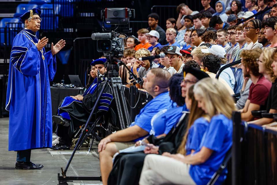 博彩网址大全 President Fred Pestello wearing academic regalia addressing students in arena seating at convocation