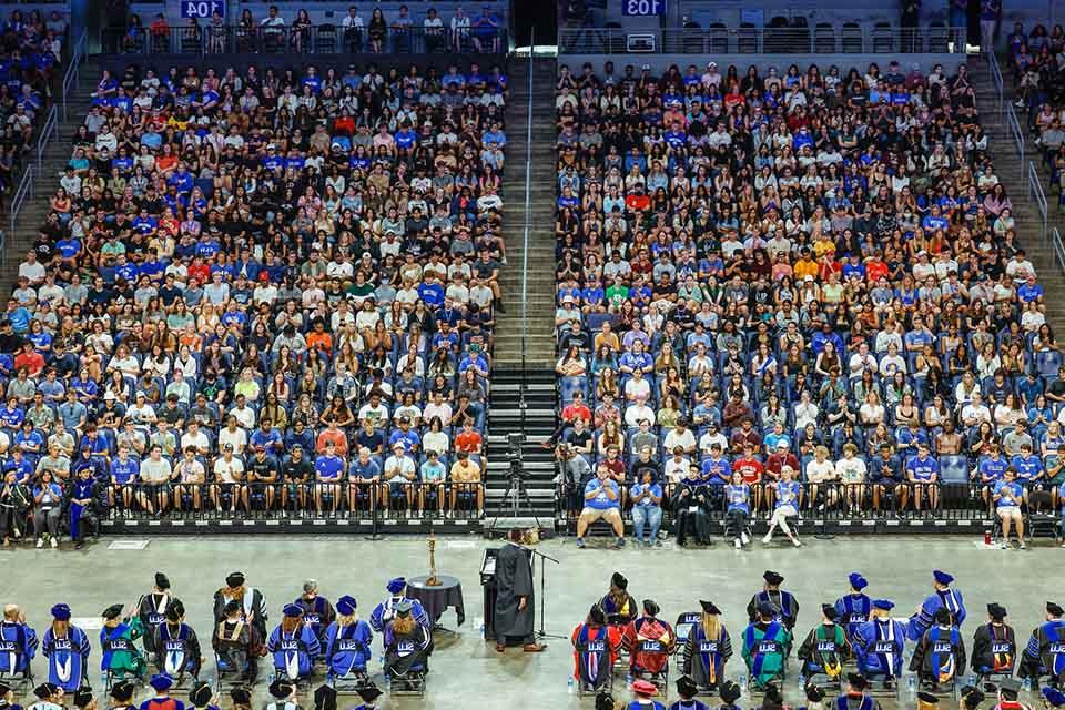 Students in arena seating seen from a distance listening to a speaker at 博彩网址大全's convocation ceremony